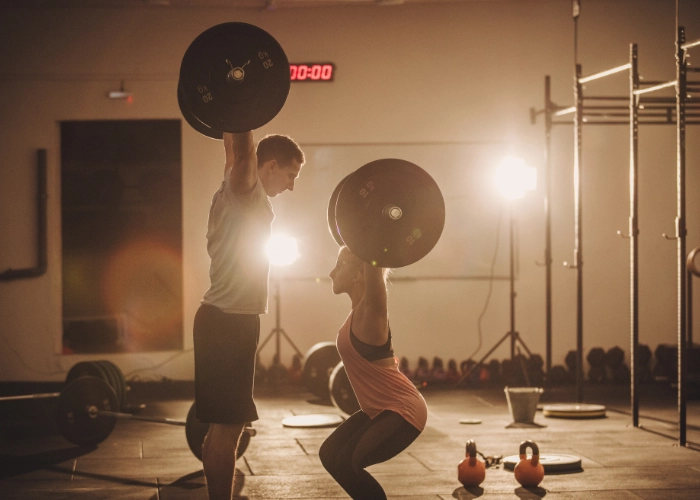 Hombre y mujer realizando un entrenamiento de fuerza en gimnasio